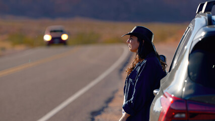 Young woman on a road trip through the desert leaning against her car - travel photography