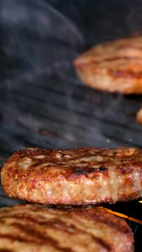 Cooking burgers on a hot grill with a flame Beef cutlets cooked on a barbecue grill.Cooking beef and pork patty for party.