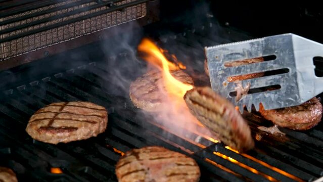 Cooking burgers on a hot grill with a flame Beef cutlets cooked on a barbecue grill.Cooking beef and pork patty for party.