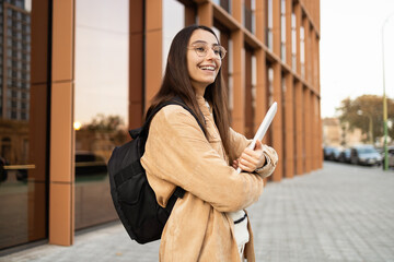 Smiling student with backpack outside college building