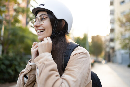 Smiling woman fastening helmet in urban setting