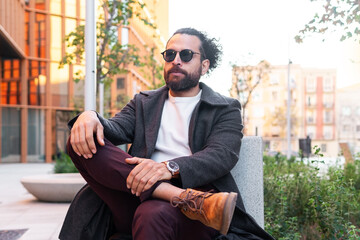 Stylish man sitting outdoors in an urban environment