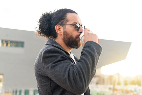Man sipping coffee outdoors with modern architecture
