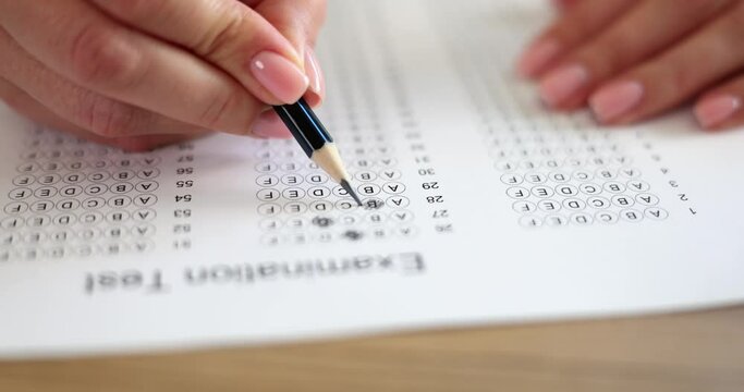 Woman hand holds pencil and marks answers to test. Hiring testing concept
