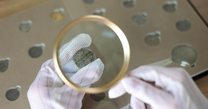 Numismatist examines coin from ancient collection. Numismatics and expert evaluation of the value of coins