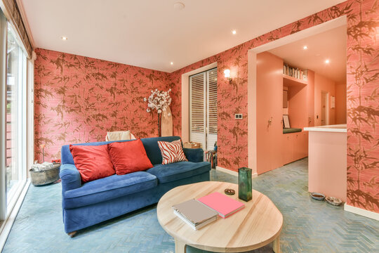 Living room with blue couch and pink wallpaper
