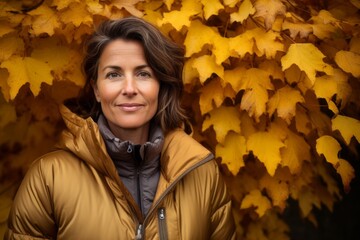 Naklejka na ściany i meble Portrait of a tender woman in her 40s donning a durable down jacket against a background of autumn leaves. AI Generation