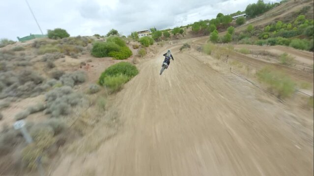 Aerial view of a speeding motocross bike jumping on a sand track