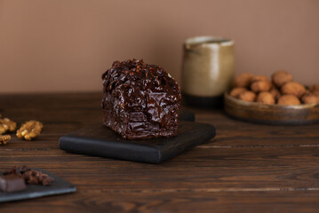 Chocolate cake with vanilla cream cheese and walnuts on a wooden table.