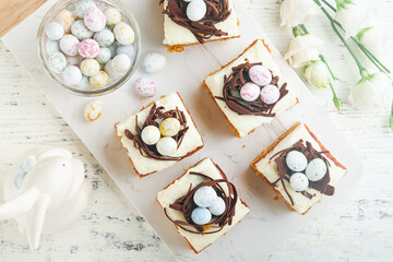 Easter carrot cake bars decorated with chocolate nest and chocolate candy eggs blossoming cherry or...