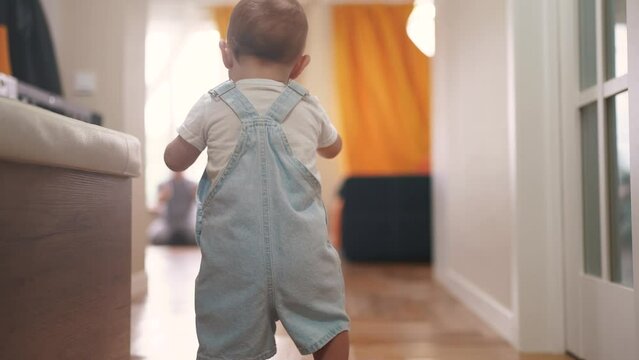baby first steps. baby goes to her father at window learns to walk to take first steps. happy family kid dream concept. dad calls son baby first steps indoors. happy family indoors lifestyle concept