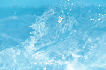 Bluewater waves on the surface ripples blurred. Defocus blurred transparent blue colored clear calm water surface texture with splash and bubbles. Water waves with shining pattern texture background.