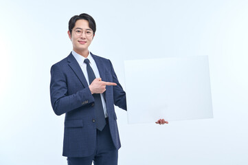 A handsome Asian man wearing a suit and glasses is holding a white sign and making various facial expressions and gestures.