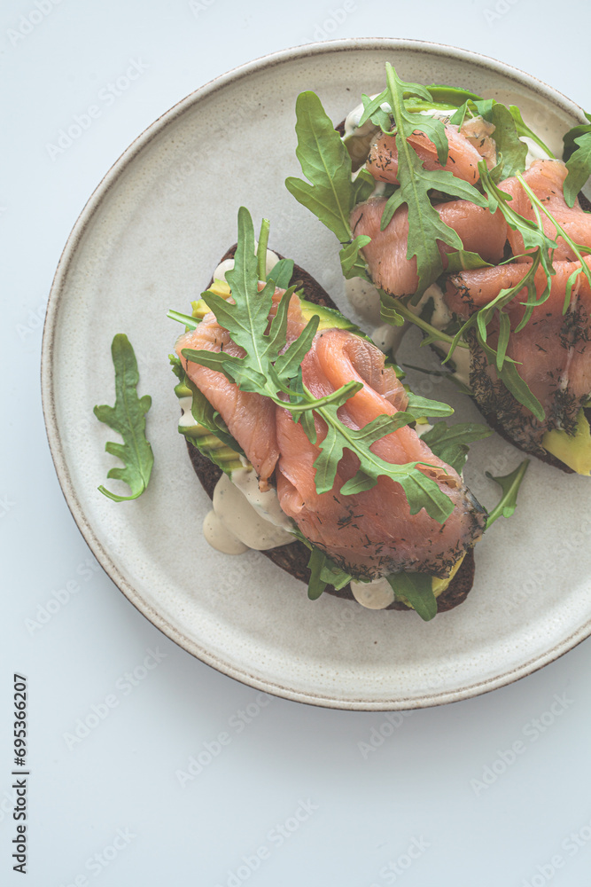 Wall mural Rye toast with smoked salmon, avocado, hollandaise sauce and arugula.