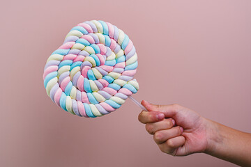 A child holds a candy on a stick. Heart-shaped candy. Valentine's day, birthday.