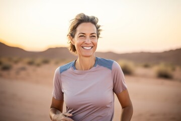 Fototapeta na wymiar Portrait of a blissful woman in her 40s wearing a moisture-wicking running shirt against a backdrop of desert dunes. AI Generation
