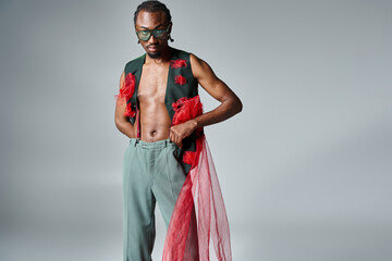 trendy african american man with sunglasses in vibrant attire looking at camera, fashion concept