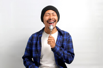 Excited, hungry young Asian man, donning a beanie hat and casual shirt, envisions delicious food,...