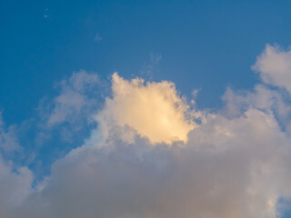 Blue sky background with clouds. Reflection of sun rays on cloud.