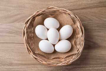 Organic white leghorn egg from free range farm in basket on wooden table, Top view - obrazy, fototapety, plakaty