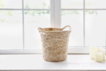 Basket and candles in front of a window shedding light on the interior of boho style living room
