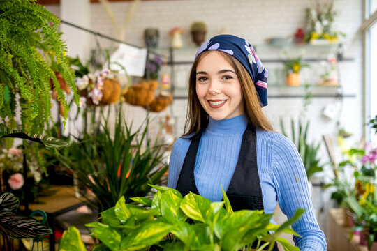 Young smiling woman with Epipremnum aureum in planter in floristry