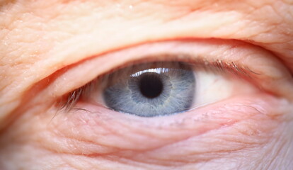 Close-up of elderly mans eye. Macro shot of senior male looking in camera. Beautiful blue colour...