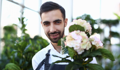 Bearded Male Florist with White Blooming Hydrangea. Smiling Gardener Holding Hortensia with Green...