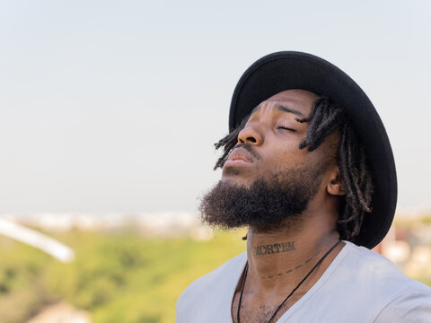 Black man with tattoo on neck standing outdoors