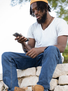 Black man messaging on smartphone in park