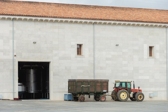 Tractor parked outside industrial area on road near storage tank placed inside factory house