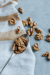 on a gray background there is a yellow striped kitchen towel, on it there is a spoon with peeled walnuts