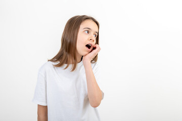 A girl with mouth wide open holds her hand near face on a white background.
