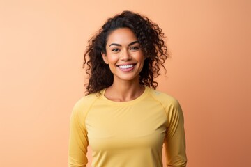 Portrait of a smiling indian woman in her 30s wearing a moisture-wicking running shirt against a pastel yellow background. AI Generation