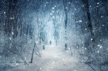 man walking through blizzard in winter forest