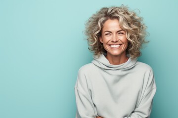 Portrait of a glad woman in her 40s dressed in a comfy fleece pullover against a pastel teal background. AI Generation - obrazy, fototapety, plakaty