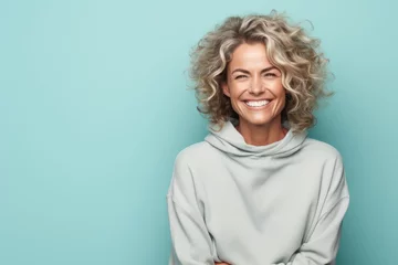 Fotobehang Portrait of a glad woman in her 40s dressed in a comfy fleece pullover against a pastel teal background. AI Generation © Markus Schröder