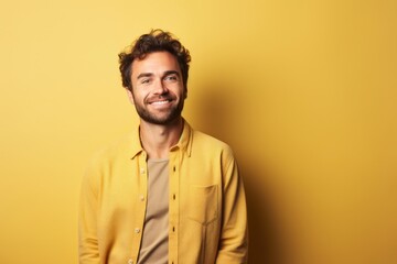 Obraz premium Portrait of a smiling man in his 30s wearing a chic cardigan against a soft yellow background. AI Generation