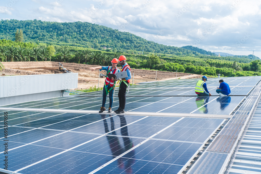 Wall mural professional worker cleaning solar panels with brush and washing with water on roof structure of bui