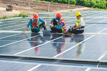 Professional technicians carrying photovoltaic solar moduls on factory roof, Engineers in helmets...