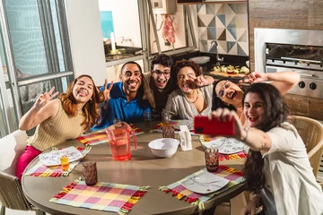 Fotobehang Grupo de amigos tirando uma selfie durante um agradável almoco. © Brastock Images