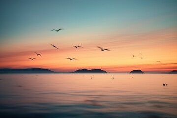  a flock of seagulls flying over a body of water with a sunset in the back ground and a small island in the middle of the water in the foreground.