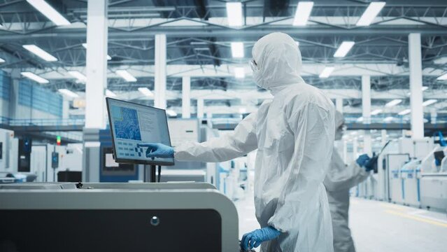 Printed Circuit Board Production In Electronics Factory Research Center: Scientist In Sterile Suit Using Soldering Jet Printer To Make Motherboards For Powerful CPU. Hardware Manufacturing Facility.