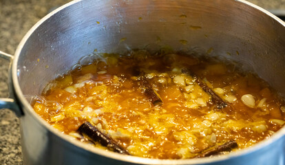 Homemade pumpkin jam with almonds and cinnamon rolls being boiled and prepared in a iron pan