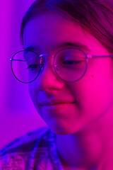 Portrait of a teenage girl with glasses in neon light.