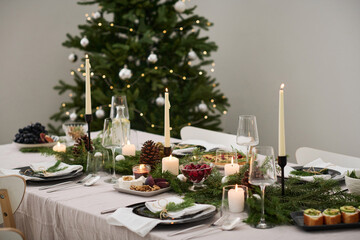 Fully arranged christmas table with festive decorations and food, christmas tree on background