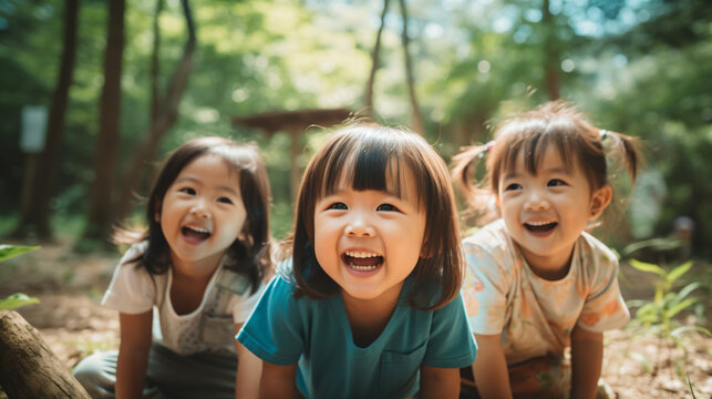日本の幼稚園児3人が私服で横に並んで笑っている写真、背景夏の自然の森、森のようちえん