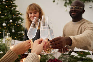 Biracial group of friends clinking glasses enjoying christmas festive dinner, focus on drinks