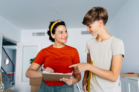 Mother and son checking notes on clipboard together and smiling