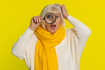 Investigator researcher scientist senior old woman holding magnifying glass near face, looking into...